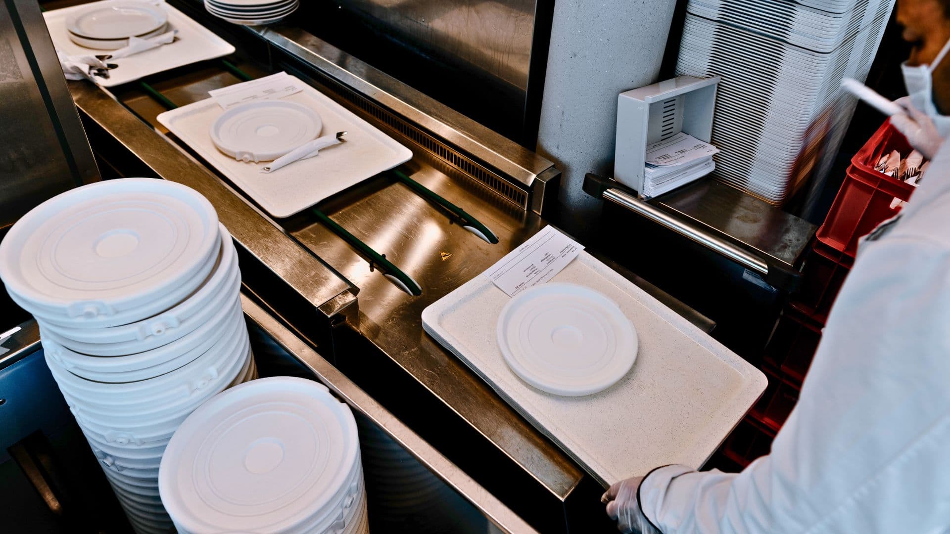 Loading trays with cutlery and crockery on the food distribution conveyor